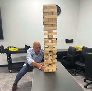 Timothy Cormier steadying a giant Jenga tower at work